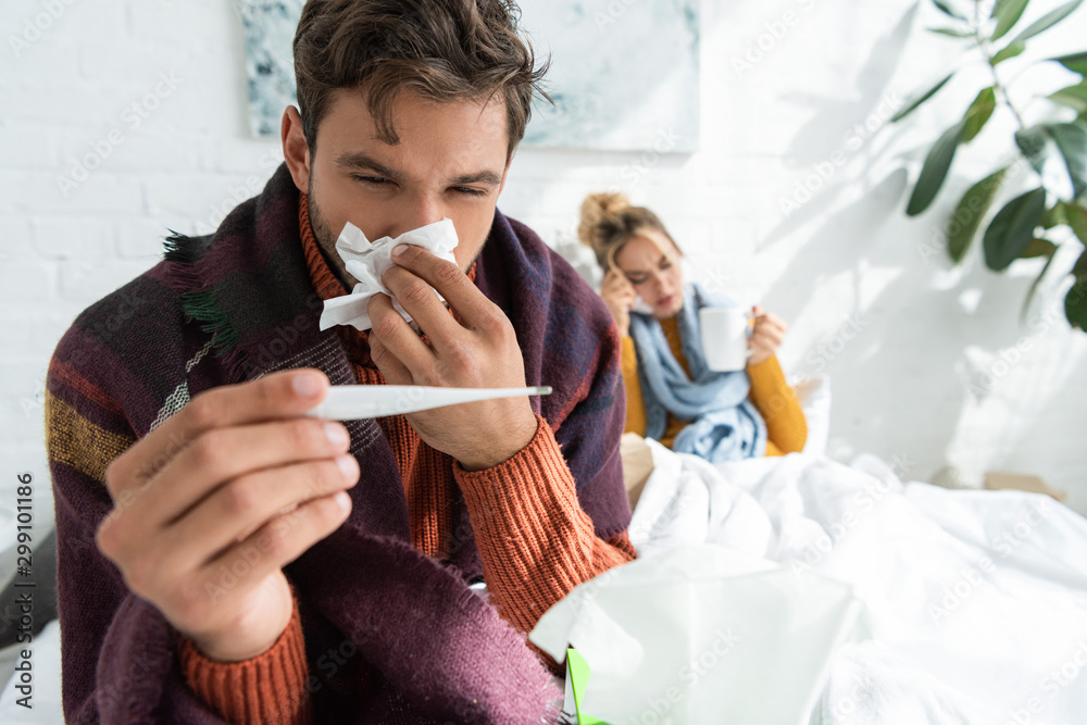 sick man with fever holding thermometer that could benefit from payment protection insurance