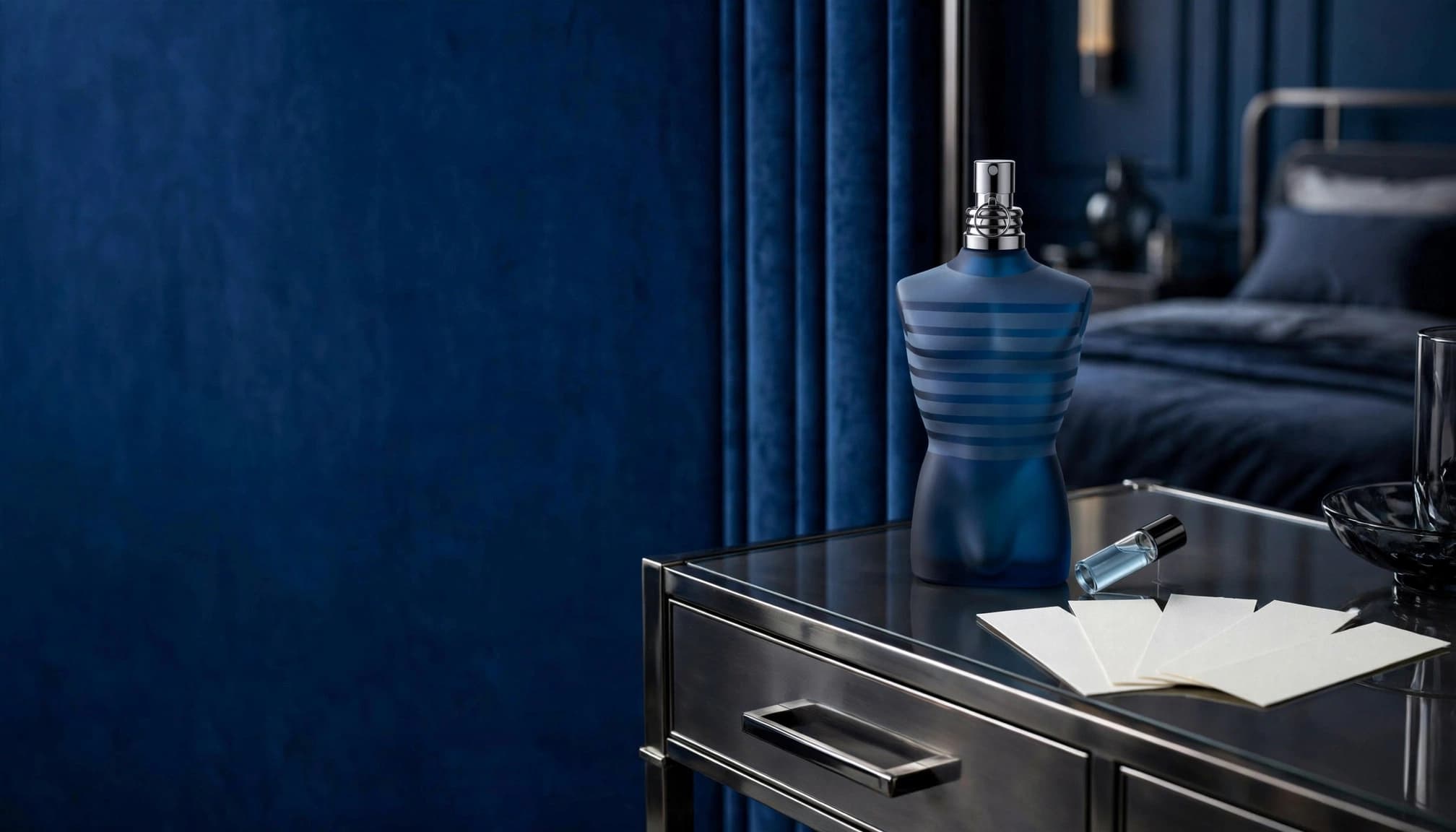 A blue fragrance bottle, sample vial, and blotter cards on a luxury dressing table.