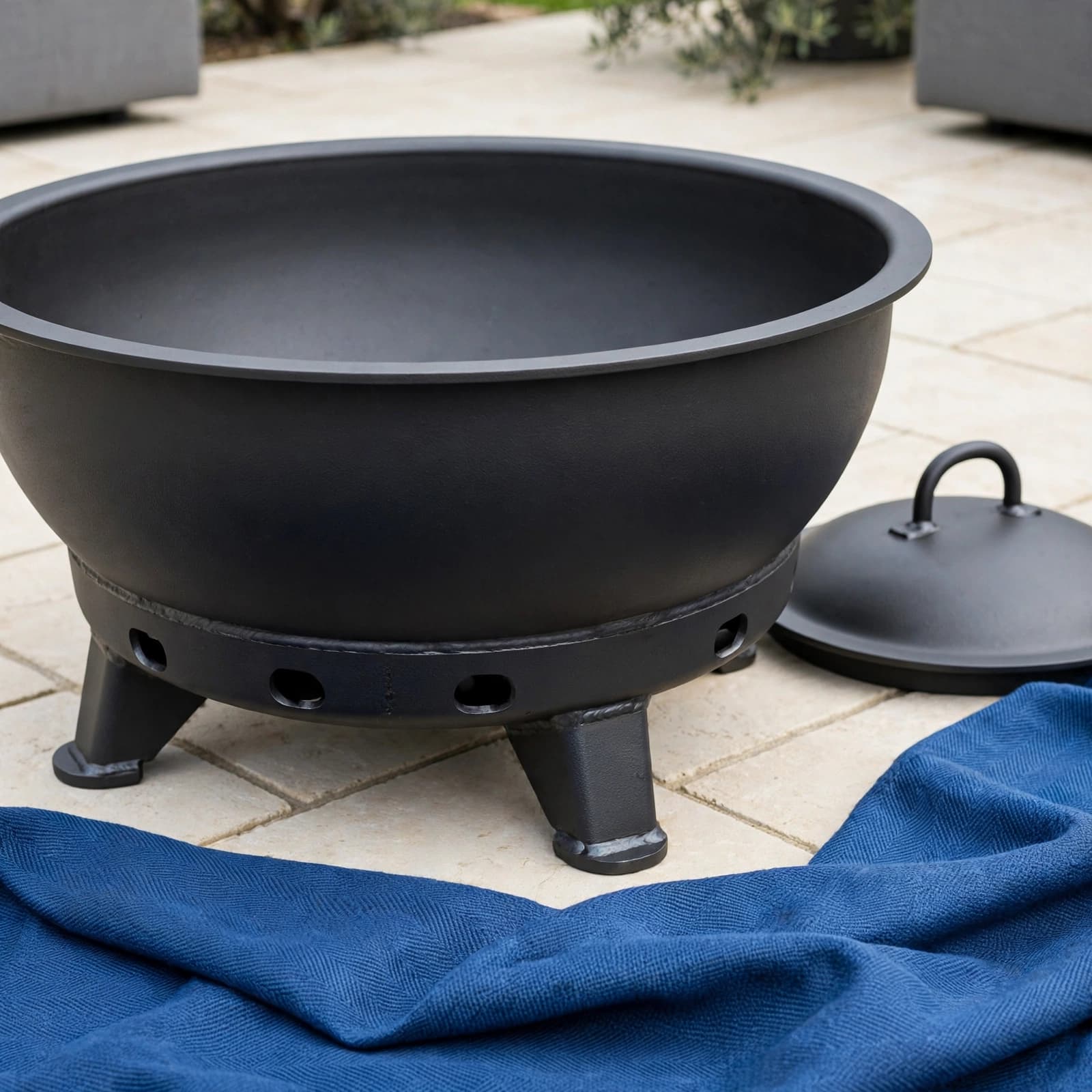 Covered Fire Pit: A UK Buyer's Guide 2 Covered steel fire pit with sturdy feet and blue textile on pale paving.