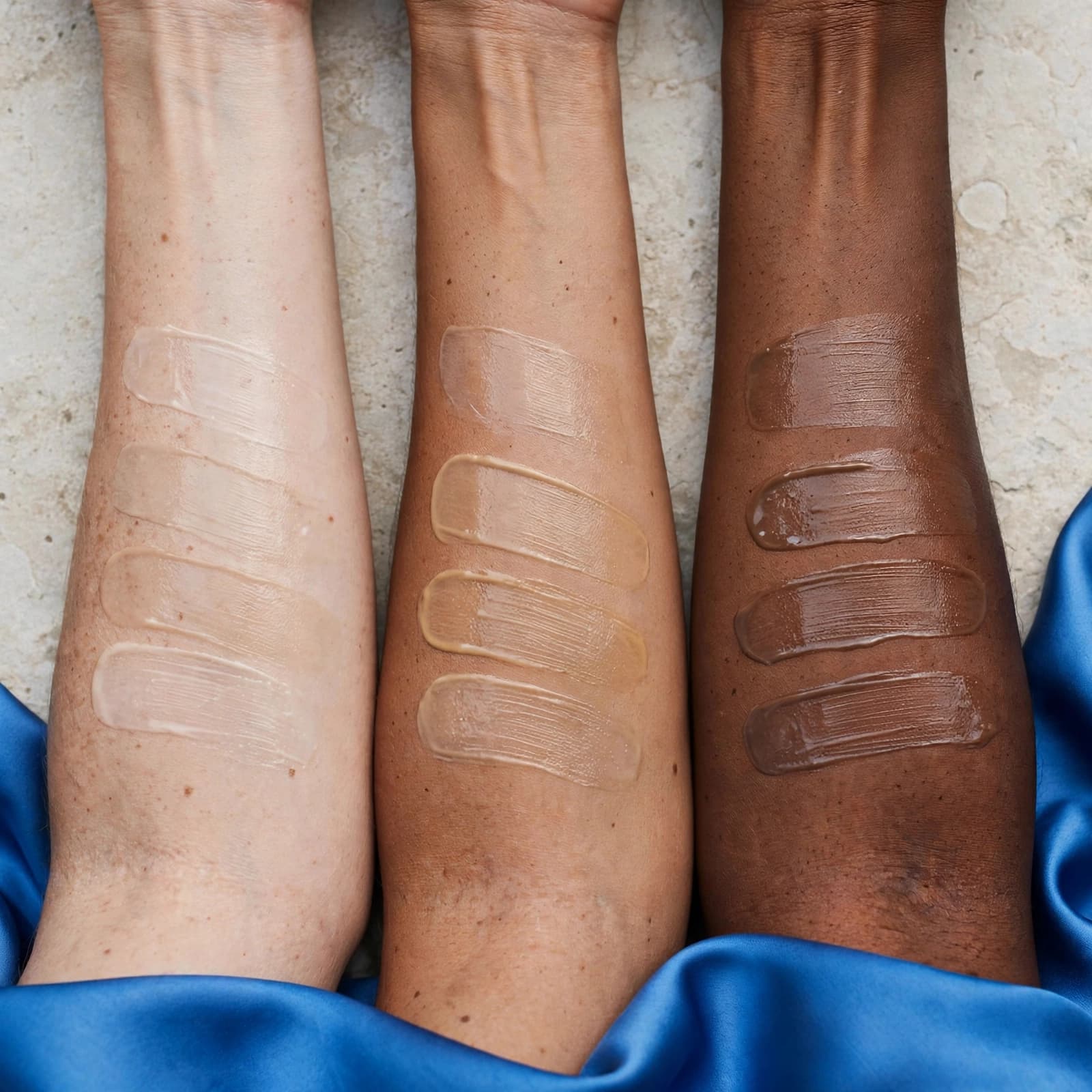 Best Tinted Moisturiser: Find Your Everyday Match 2 Sheer tinted moisturiser swatches on three forearms with light, medium, and deep skin tones.