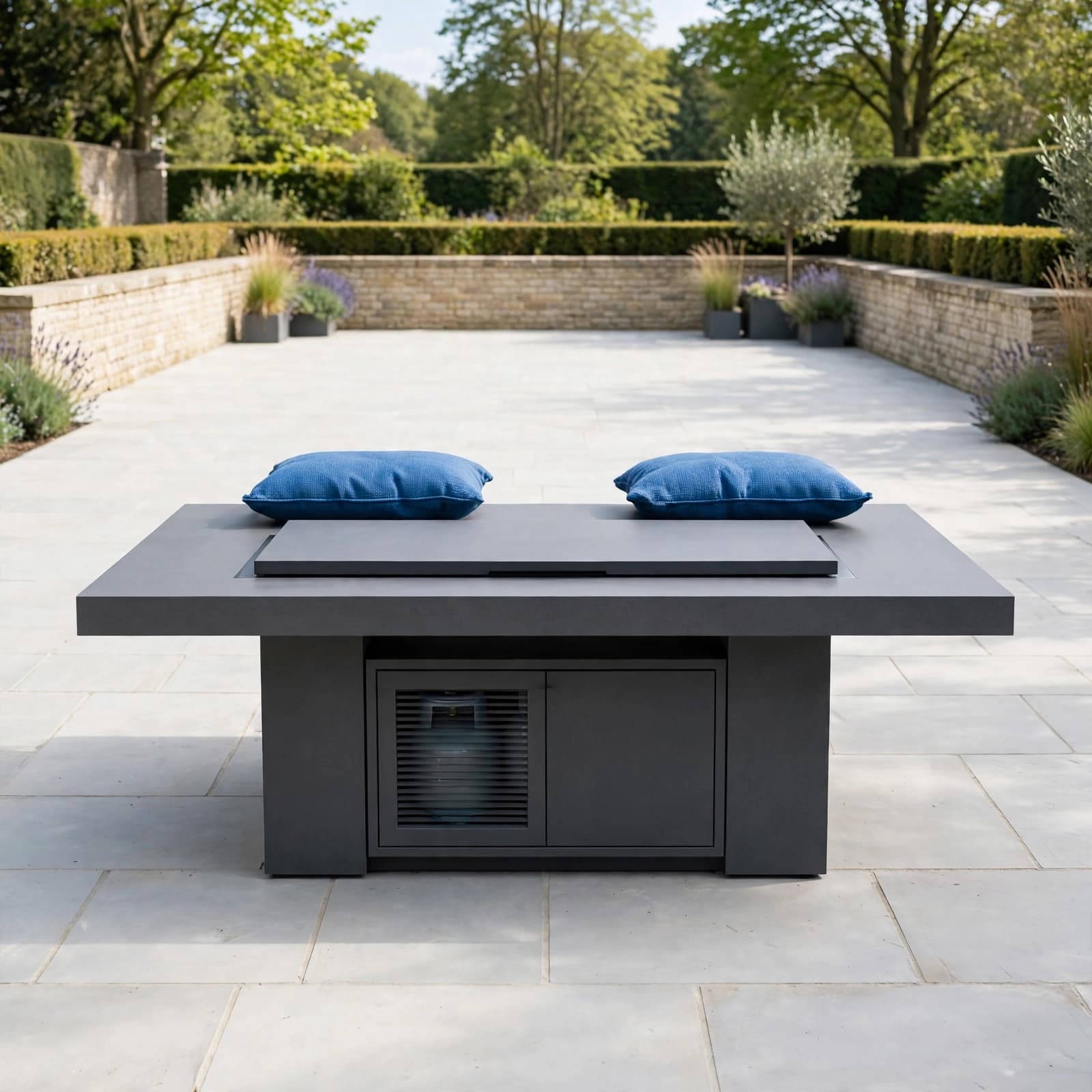 Covered Fire Pit: A UK Buyer's Guide 3 A gas fire table sits in an open paved courtyard with blue cushions and clear space around it.