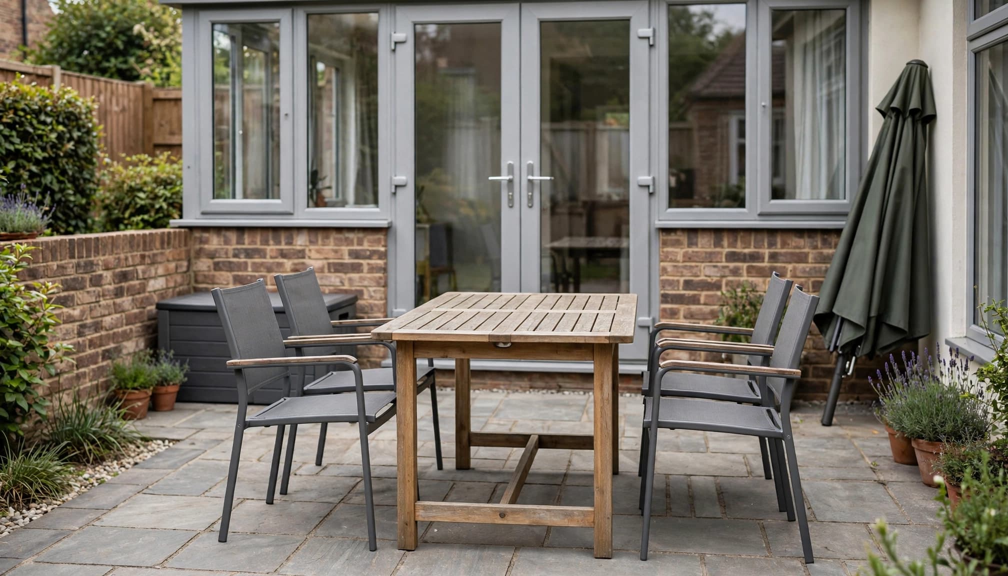 Four chairs surround a garden table with walking space on a compact patio.